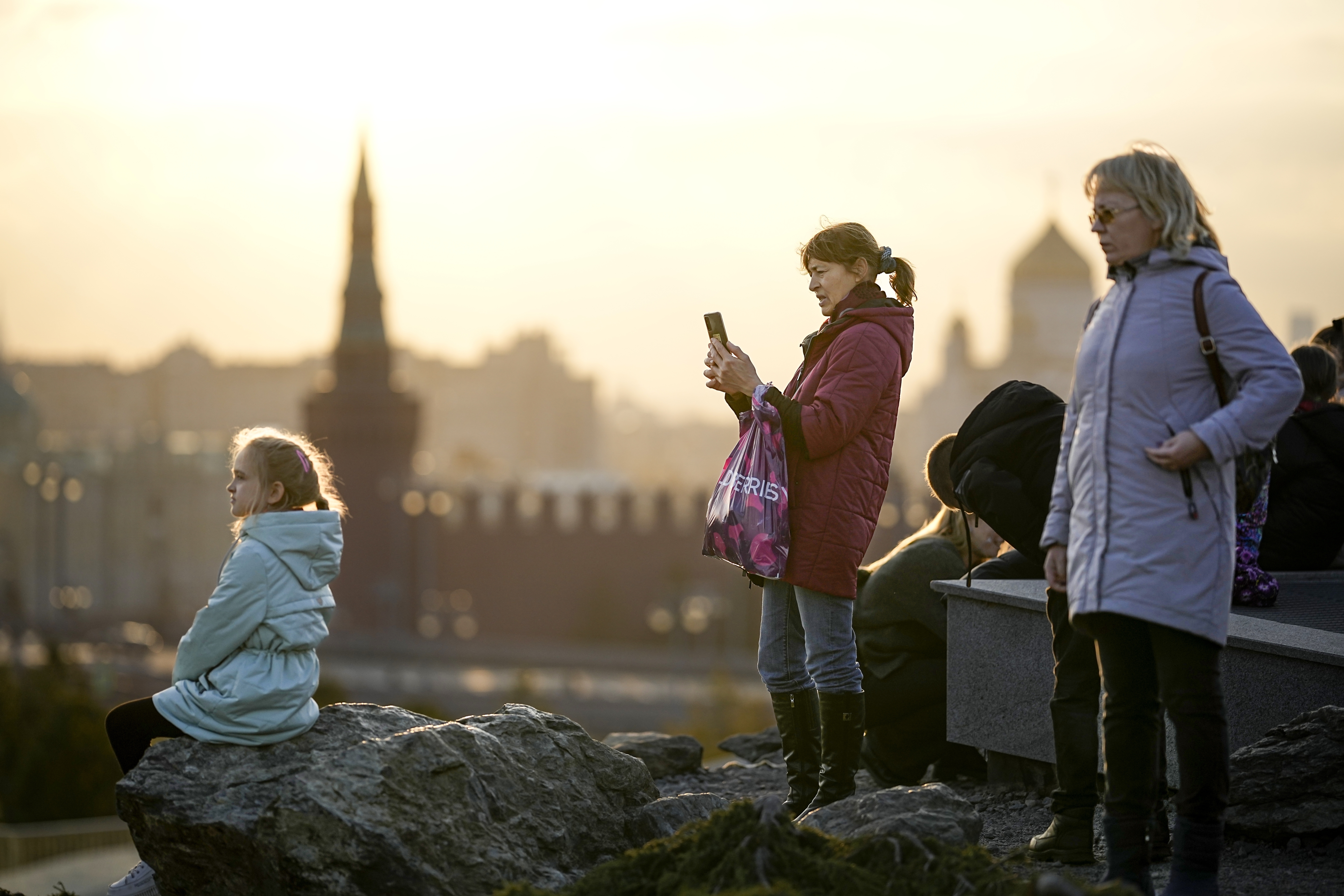 People enjoy a warm autumn sunset at Zaryadye Park near Red Square with the Kremlin in the background in Moscow, Russia, on Wednesday, Nov. 1, 2023. The temperature in Moscow rose to 14 degrees Celsius (57,2 Fahrenheit) and broke the 1934 record by 1.5 degrees Celsius, which is unusual for the beginning of November. (AP Photo/Alexander Zemlianichenko)